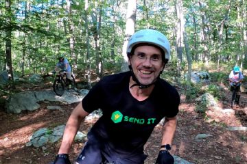 Tim on his trials bike, smiles at the camera. He's wearing a Sam Pilgrim "Send It" t-shirt.