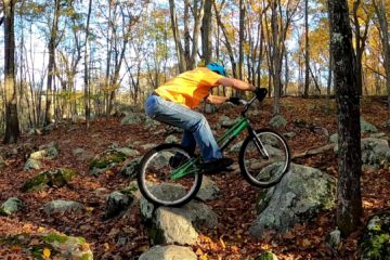 Jim balances his trials bike between two rocks