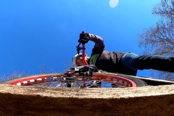 Tim rides his trials bike across a narrow wooden beam