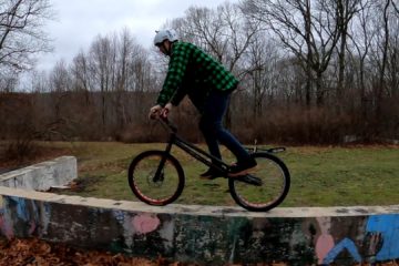 Tim rides his trials bike across a graffiti-covered wall