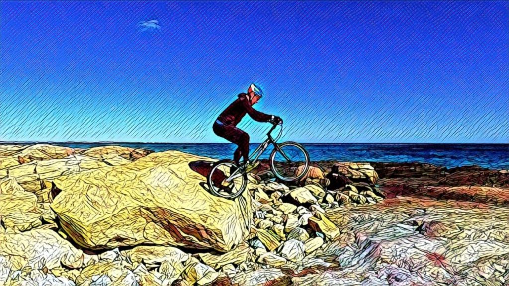 Vlasta hops off a boulder, with the ocean in the background
