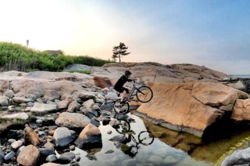 On his bike's rear wheel, Mike balances on a small rock surrounded by water just before hopping up onto a boulder