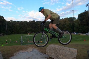 Biking across rocks with soccer practice in the background