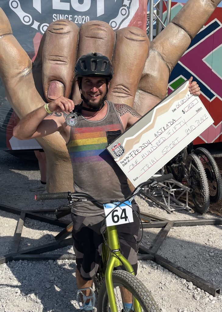 Freddy Astrada holding up his medal and prize check