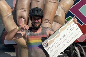 Freddy Astrada holding up his medal and prize check
