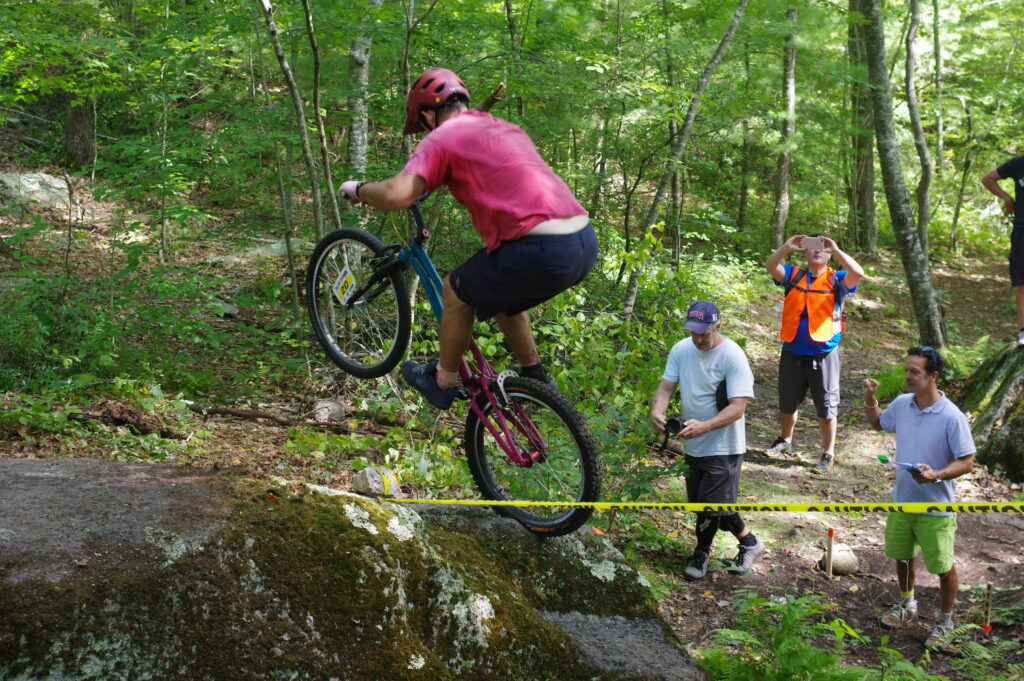 Trials biker balances on his rear wheel on a rock during a competition