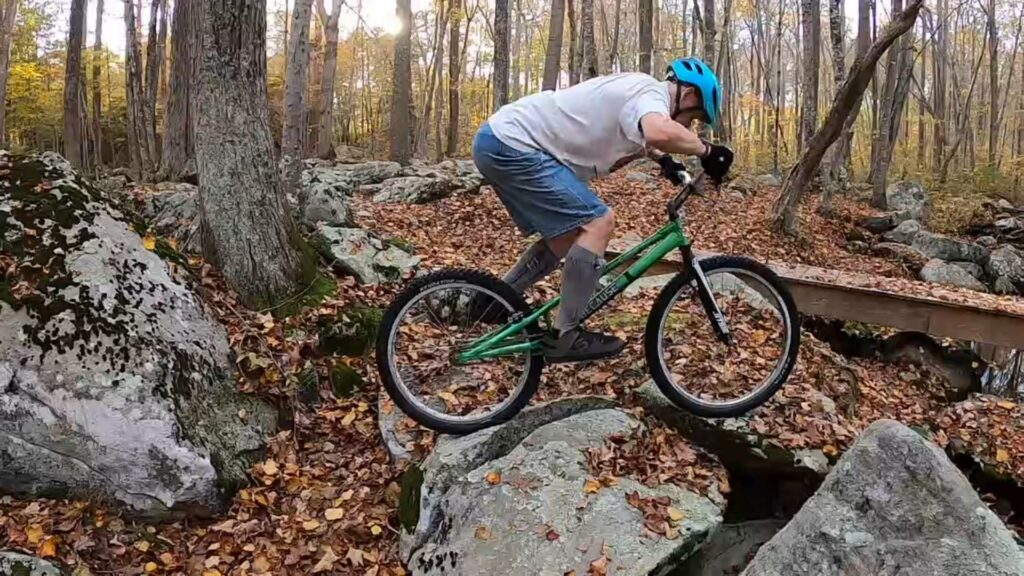 Jim hops his trials bike onto some rocks next to the creek