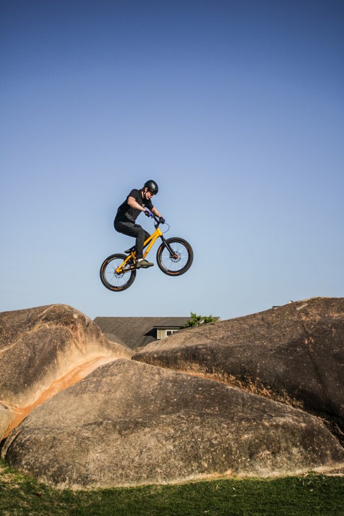Nathaniel Moore does a big gap on his trials bike, atop a huge boulder