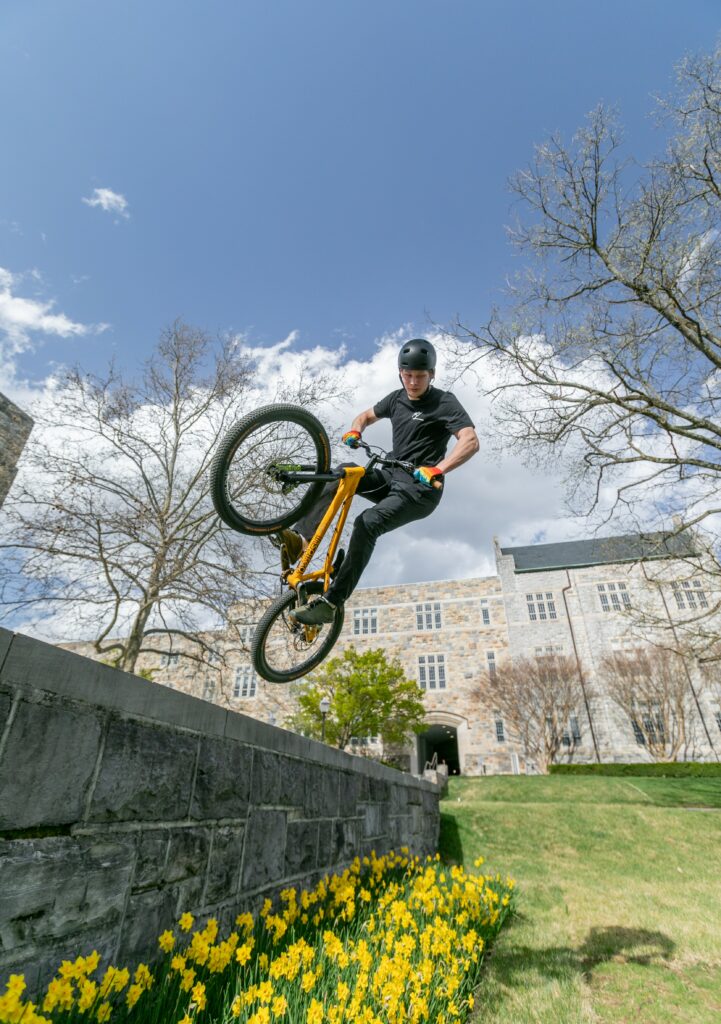 Nathaniel Moore doing a tire tap off a wall and across a patch of daffodils